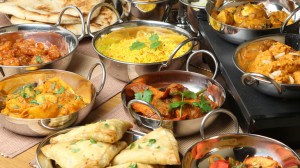 Selection of Indian food including curries, rice, samosas and naan bread.