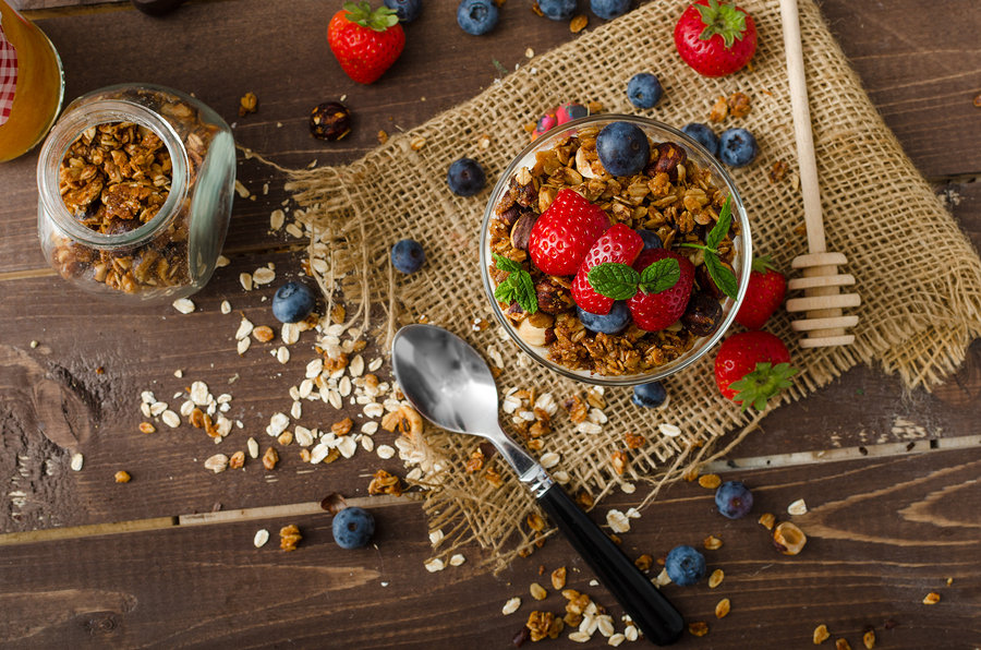 Yogurt with baked granola and berries in small glass strawberries blueberries. Granola baked with nuts and honey for little sweetness. Homemade yogurt