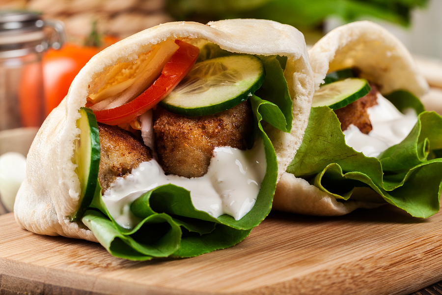 Pita bread with falafel and fresh vegetables on wooden table