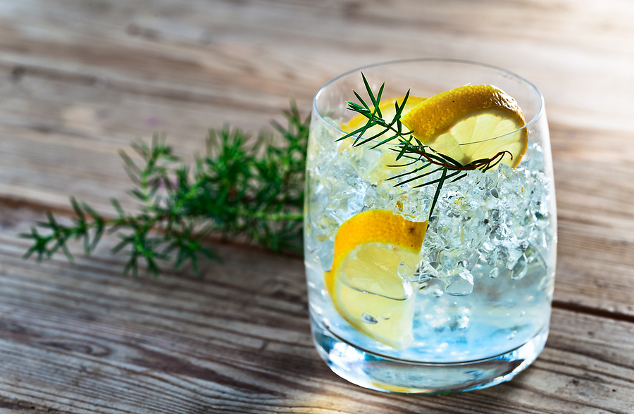 Gin with lemon and juniper branch on a old wooden table