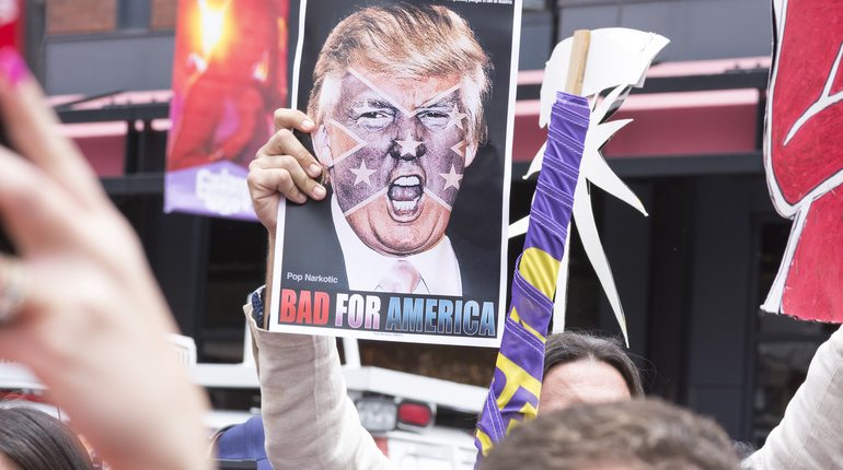 SAN DIEGO USA - MAY 27 2016: A protester holds a sign featuring an angry photo of Donald Trump and reading "Bad for America" at an anti-Trump protest outside a Trump rally in San Diego.