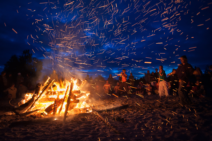 Leningrad Oblast Russia - July 14 2015: Big tourist bonfire on the beach Finland Gulf during the festival. Young people dance and sing around the campfire. Deep night.