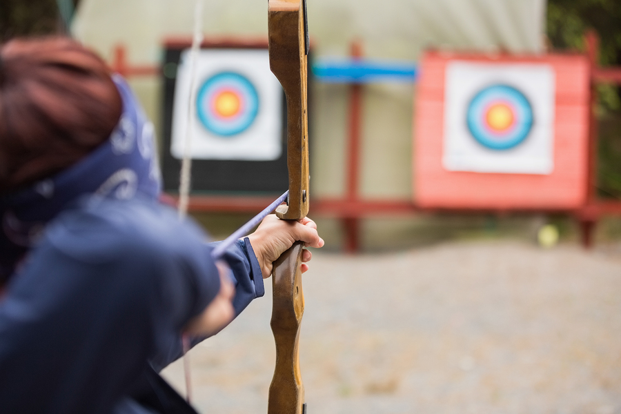 Brunette about to shoot arrow at the archery range